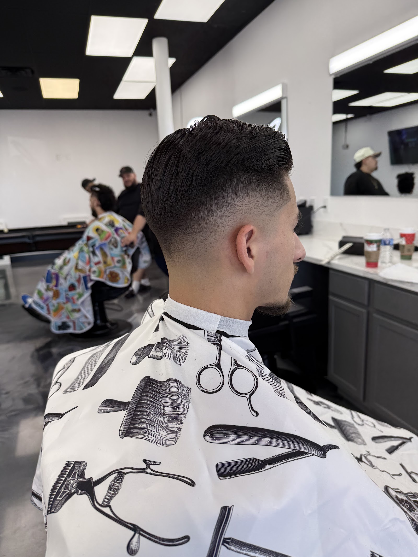 Client with a fresh tapered fade and styled top wearing a barber cape