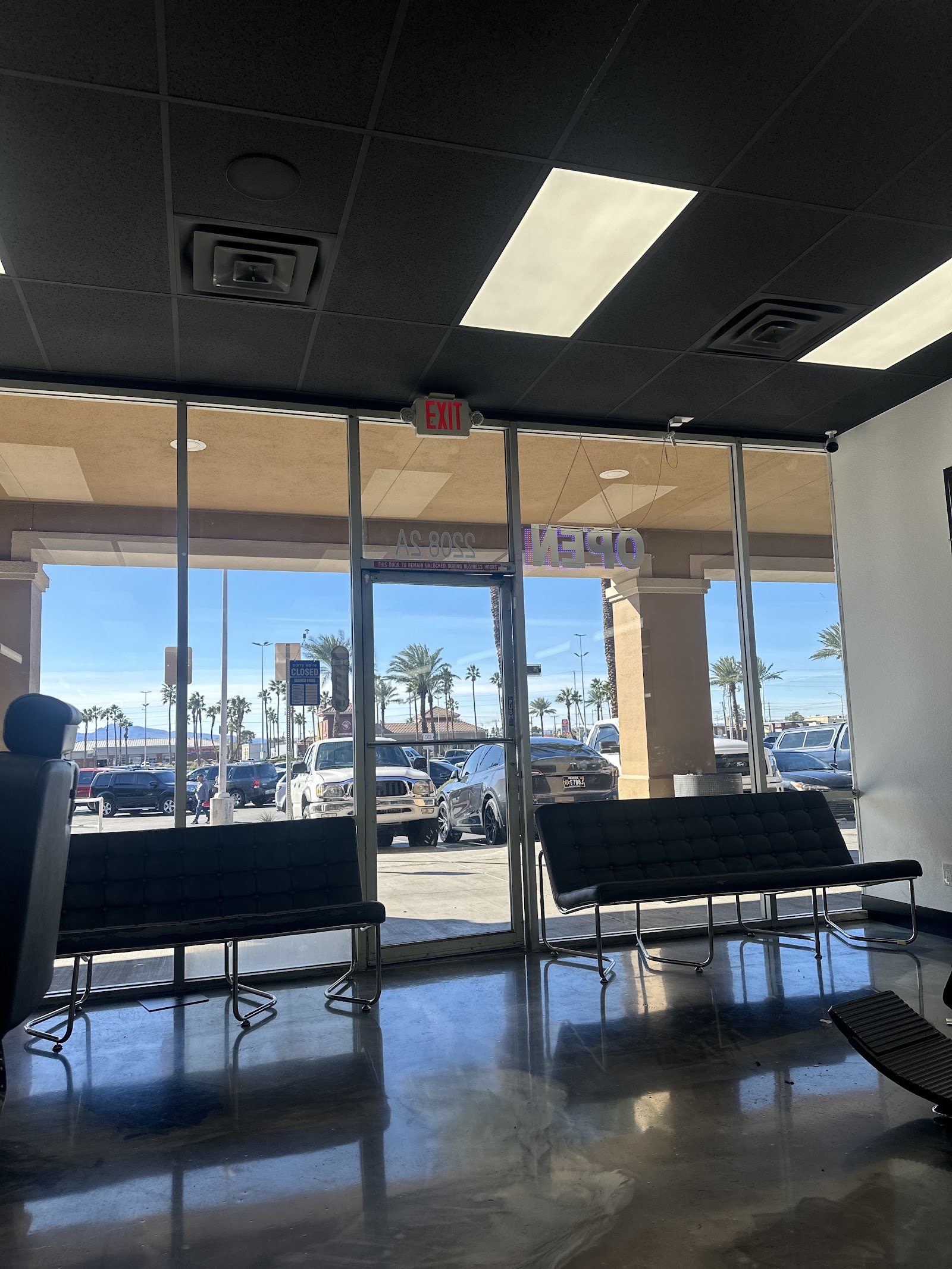 Barbershop waiting area with black benches and a view of the parking lot through the glass storefront